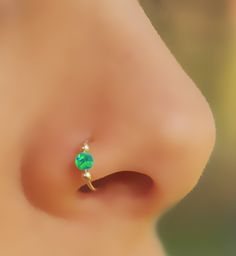 a close up view of a person's nose with a green stone on it