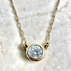 A spectacular vintage 14 karat yellow and white gold solitaire pendant necklace featuring a 5.25 mm natural round diamond weighing approximately 0.60 carat. It is G-H in color and VS2 in clarity. The necklace is 15 inches long. The bezel is 7.50 mm in diameter. The chain is 1.25 mm thick and equipped with a safety snap tab. Weighs 3.42 grams. Stamped 14K. Birthstone: April. Condition: Very good. Light scratches and wear throughout metal. - 14 day return policy, no questions asked. - Free insured Classic 14k Yellow Gold Solitaire Necklace, Classic Solitaire Necklace With Bezel Setting, Classic Round Cut Diamond Necklace With Bezel Setting, Vintage Brilliant Cut Diamond White Necklaces, Classic 14k Gold Solitaire Necklace With Round Pendant, Classic Yellow Gold Solitaire Diamond Necklace, Yellow Gold Solitaire Necklace With Round Stone, Timeless Yellow Gold Solitaire Necklace With Round Stone, Classic Bezel Set Round Diamond Necklace