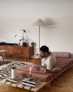 a man sitting on top of a couch in a living room next to a coffee table