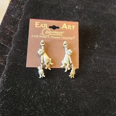 pair of gold tone earrings with small white dog on it's back and ears