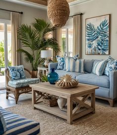 a living room with blue and white decor on the walls, couches, coffee table and potted palm tree