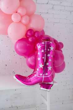 a pink boot with stars and balloons hanging from it