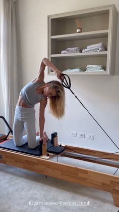 a woman is doing exercises on an exercise machine in her living room while holding onto the handle bars