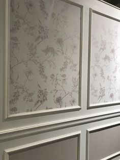 the wallpaper is white and has flowers on it, as well as silver trim