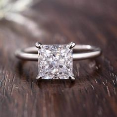 a princess cut diamond engagement ring on a wooden table with the words lovemark jewelry