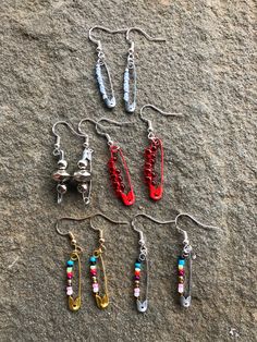 six pairs of earrings are laid out on the ground, including one with beads and two without