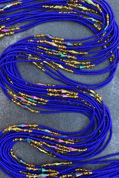 blue beaded necklaces are lined up on the ground