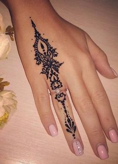 a woman's hand with a black and white henna tattoo design on it