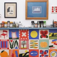 a kitchen counter decorated with colorful tiles and pictures on the wall, along with spices and condiments