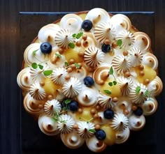 a cake with white frosting and blueberries on top is shown in the shape of a flower