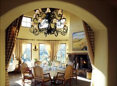 a dining room with a chandelier hanging from the ceiling and chairs around it