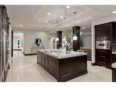 a large kitchen with marble counter tops and dark wood cabinets