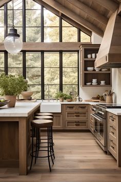 a kitchen with wooden floors and lots of counter space in the center, along with large windows