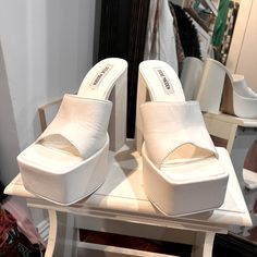 White Modern 4-inch Heels For Spring, White Square Toe Heels With 4-inch Heel, Modern White Mules With Sculpted Heel, White Square Toe Mules With Branded Heel, Trendy White Wedge Heels, Chic Wedge Heels With Padded Heel, White Platform Heels In Trendy Style, Chic Padded Wedge Heels, Trendy White Heels For Spring