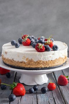 a cake topped with fresh berries on top of a wooden table