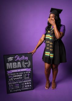 a woman wearing a graduation cap and gown standing next to a sign