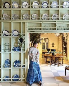 a woman standing in front of a wall with plates on it