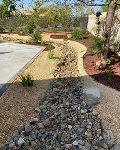 a rock garden bed in front of a house with gravel and rocks on the ground