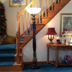 a blue carpeted hallway with stairs and a lamp on the table next to it