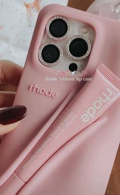 a pink phone case with some black circles on it and a tube of toothpaste next to it