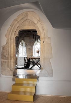 an arched doorway with yellow steps leading to the dining room table and chairs in it