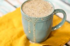 there is a blue mug with liquid in it on a yellow napkin next to some cookies