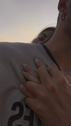 a man and woman embracing each other with the sky in the background