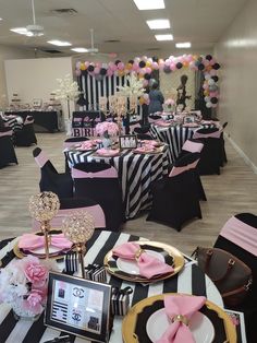 a room filled with black and white striped tables covered in pink, yellow and silver decorations