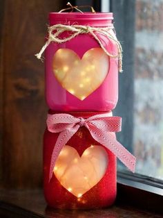 two mason jars decorated with hearts are sitting on a window sill