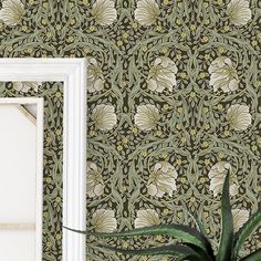 a white frame sitting next to a wall with a green and yellow floral pattern on it