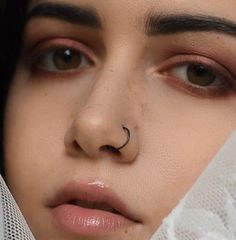 a close up of a woman with a nose ring on her nose and veil over her face