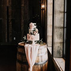 a wedding cake sitting on top of a wooden barrel