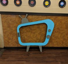 a blue tv sitting on top of a wooden floor next to a wall with records