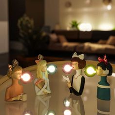 three small figurines sitting on top of a table with lights in front of them