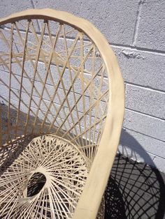 a wicker chair next to a brick wall with shadows on the floor and in front of it