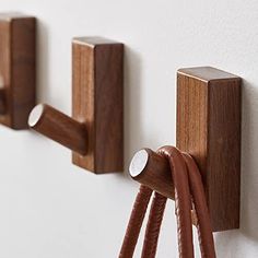 three pieces of wood are attached to the wall with hooks and cords on each side