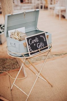 an open suitcase sitting on top of a table next to a chalkboard sign that says candie and gifts