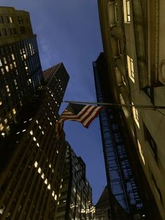 an american flag flying in the air between two tall buildings