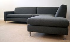 a gray couch sitting on top of a wooden floor next to a white wall in a living room