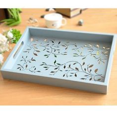 a blue tray sitting on top of a wooden table next to flowers and a cup