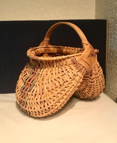 two wicker bags sitting on top of a white table next to a black wall