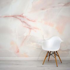 a white chair sitting in front of a wall with a pink marble design on it