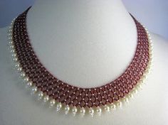 a red and white necklace with pearls on it's collarline, sitting on a mannequin