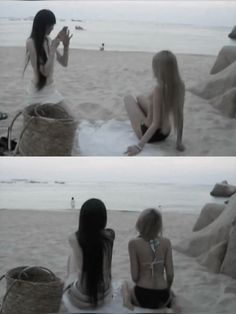 two women sitting on the beach talking to each other