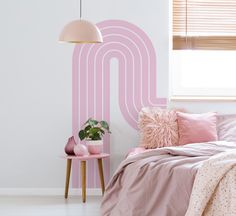 a bedroom with pink bedding and pillows on the floor next to a wall that has a letter n painted on it