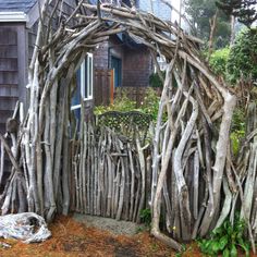 a wooden fence made out of branches in front of a house