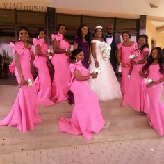 a group of women in pink dresses posing for a photo on the steps at a wedding