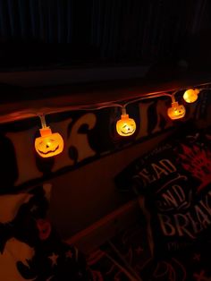 some lights that are on the side of a wall with pumpkins hanging from them