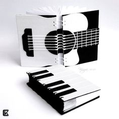 an open book with black and white designs on the cover, sitting next to a piano keyboard