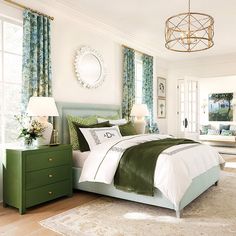 a bedroom with green and white bedding, two nightstands and a chandelier